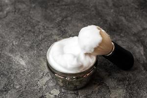 Shaving brush and cream on dark plaster background photo