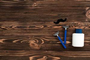 Disposable razor, cream jar on the wooden background photo