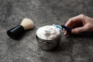 Hand holds disposable razor on gray wall background photo