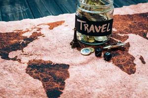 Travel budget concept. Money saved for vacation in glass jar on world map background, copy space. photo