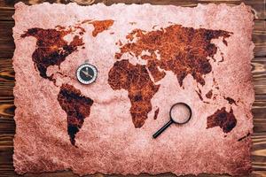 A map of the world is laid out on a wooden table photo