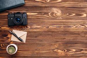 On a wooden table lies a camera, a notebook, a cactus. copy space photo