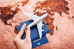 Hand holding passport on the world map background with model airplane, travel concept, selective focus photo
