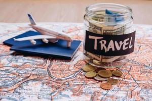 Vacation money savings in a glass jar with travel text . World map background photo
