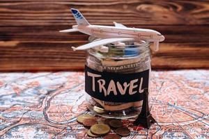 Collecting money for travel, money savings in a glass jar with world map photo