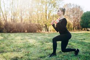 Athletic, slim girl makes lunges with dumbbells photo