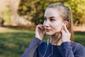 Sports girl in headphones adjusts to training photo