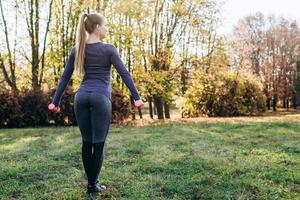 hermosa joven en ropa deportiva trabajando con pesas. concepto de deportes foto