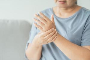Closeup of woman sitting on sofa holds her wrist. hand injury, feeling pain. Health care and medical concept. photo