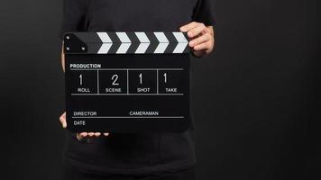 Hand is holding clap board or movie slate with write in number use in video production and movie industry on black background. photo