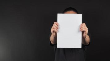 Male model's hands is holding blank A4 paper on black background. photo