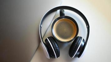 tiro de la vista superior de la taza de café con la computadora portátil y los auriculares colocados sobre una mesa en un café, lugar de la taza de café en los auriculares. foto