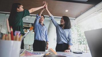 El equipo de diseñadores gráficos se tomó de la mano para expresar su alegría después de completar el trato con el cliente del proyecto. foto