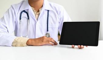 el médico usa una tableta en la mano para guiar a los pacientes en línea desde casa.