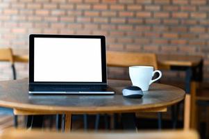 Mockup blank screen laptop with coffee on the table,Taken from the front. photo