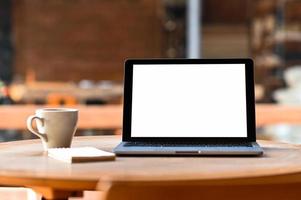 Mockup blank screen laptop with coffee and notebook on the table, Taken from the front. photo