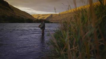 Hombre pescando con mosca en el hermoso río al amanecer. video