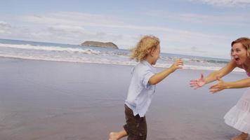 mãe balançando filho na praia. filmado em vermelho épico para alta qualidade 4k, uhd, resolução ultra hd. video