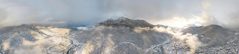 Aerial view of Krasnaya Polyana, mountains covered by snow and beautuful clouds. Russia.