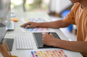 Professional graphic designers are working on digital boards with color charts on their desk. photo