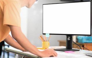 joven operando una computadora de maqueta con una gran pantalla en blanco, usando una computadora para buscar información. foto