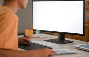 Graphic designer working on digital board with mockup computer monitor blank screen. photo