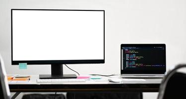 Mockup blank screen computer and laptop on a programmer desk. photo