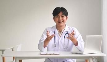 un joven médico con uniforme médico mira a la cámara para brindar consejos de salud. foto