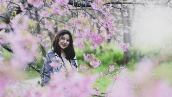 Adolescente asiática viaja felizmente tomando fotografías con flores de cerezo. foto