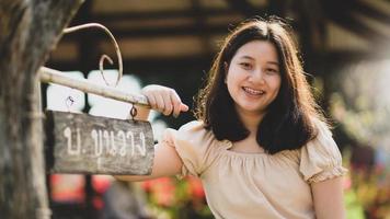 Asian teenage girl facing the camera smiling happily as she travels in nature. photo