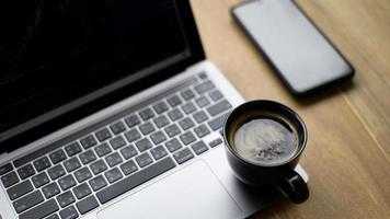 Coffee mug placed on laptop with stock chart on screen, Top view shot. photo