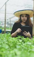 una nueva generación de agricultoras con tableta en la plantación hidropónica en invernadero, granja inteligente.
