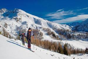 Esquí de montaña dos niñas cuesta arriba hacia una montaña