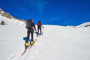 Ski mountaineering two girl uphill towards a mountain photo