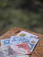Billetes australianos apilados de diferente denominación en el cuadro marrón foto