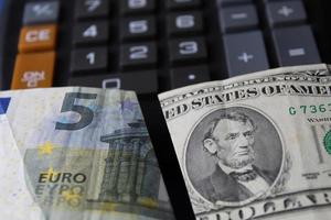 Acercamiento al billete de cinco euros y el billete de cinco dólares americanos en la calculadora foto