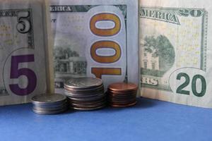 Enfoque de monedas apiladas y billetes de dólar americano de diferente denominación. foto