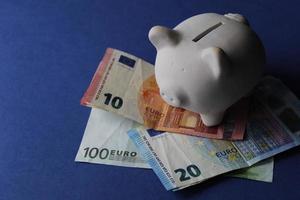 White piggy bank on the european banknotes and blue background photo