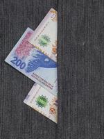 Billetes argentinos de diferente denominación entre tejido denim azul foto