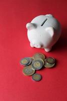 White piggy bank and Mexican coins on red background photo
