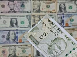 Approach to indian banknote and background with american dollar bills photo