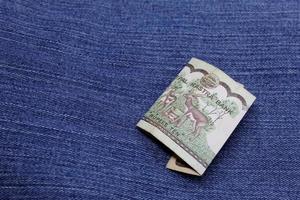 Billete de Nepal de diez rupias entre tela de mezclilla azul