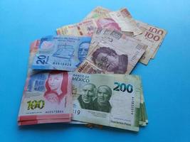 Stacked mexican banknotes of different denominations on the blue background photo