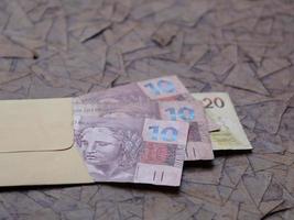 Brazilian banknotes in yellow paper envelope on brown surface photo