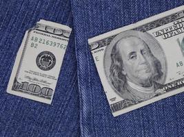 Broken american banknote of 100 dollars between blue denim fabric photo