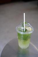 Iced matcha lemon soda on the table, Pouring green tea into a glass of honey lemon soda. photo