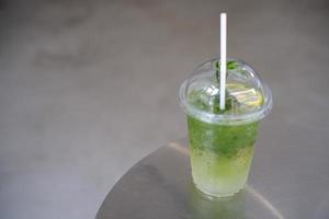 refresco de limón matcha helado en la mesa, vertiendo té verde en un vaso de refresco de limón y miel. foto