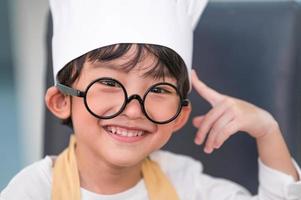 Portrait cute little Asian happiness boy interested in cooking with mother funny in home kitchen. People lifestyles and Family. Homemade food and ingredients concept. Baking Christmas cake and cookies photo