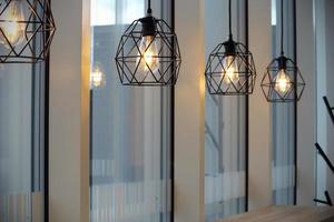 Modern cafe black metal carcass lamps near windows photo