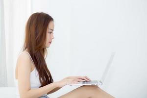 Young asian woman using laptop for leisure on bedroom. photo